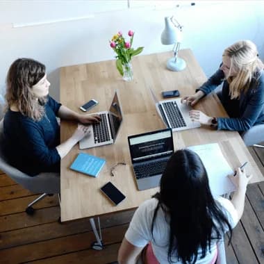 Drei Personen arbeiten gemeinsam an Laptops